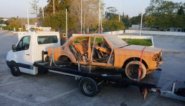 Junk car strapped onto a flatbed tow truck during a free pickup